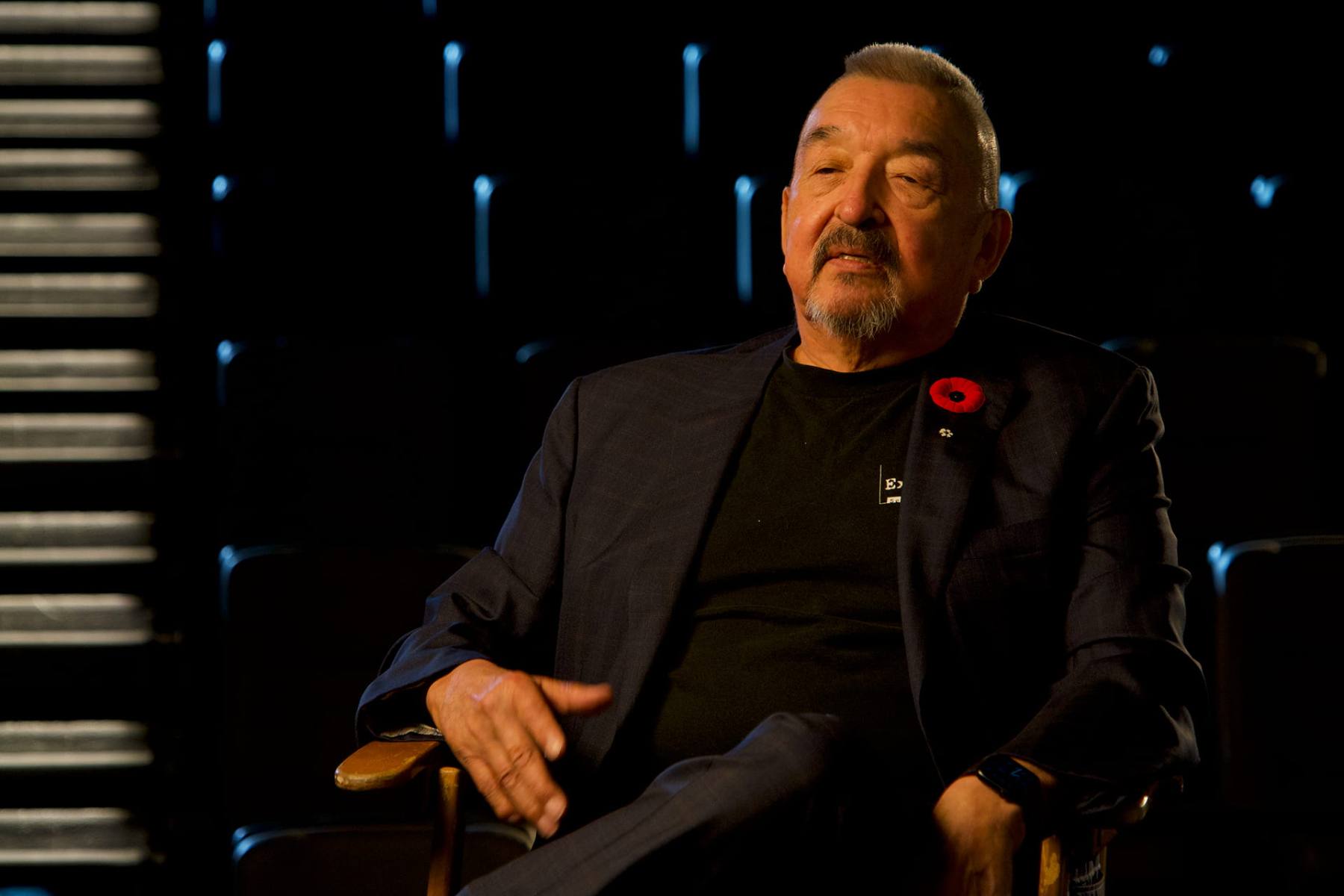 An interview subject seated in a darkened theatre