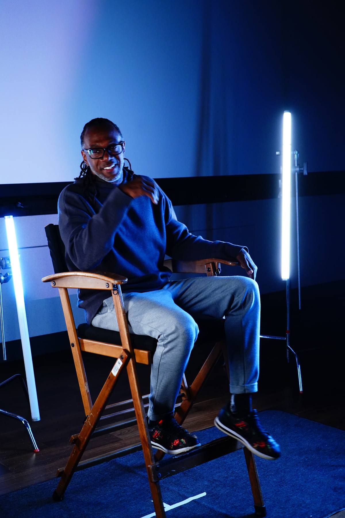 Kevin Barton seated in a director's chair on a lit set